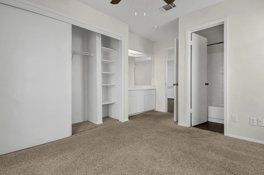 A spacious, empty room with white walls and carpeted floor.