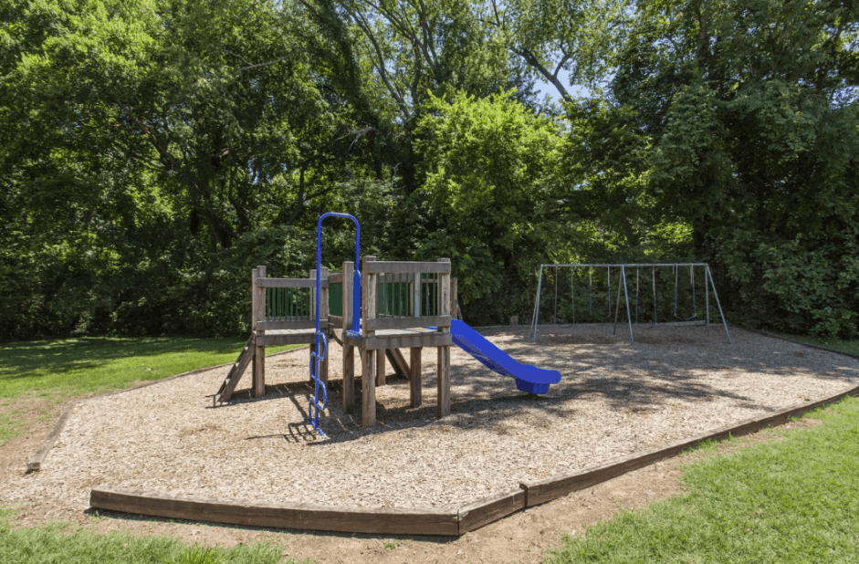 A playground with a blue slide and a wooden structure.