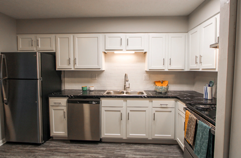 A kitchen with white cabinets and a black refrigerator.