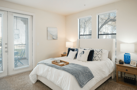 A bedroom with a white bed and a tray of food on it.