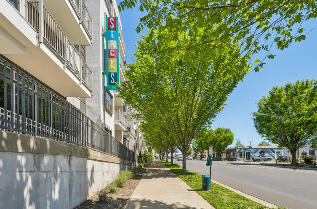 A tree with green leaves is in front of a building with a sign that says "SLS".
