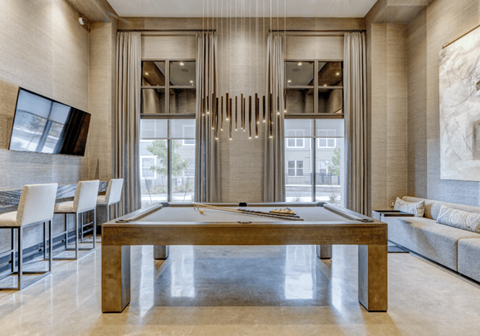 A room with a pool table and a long hanging piece of artwork.
