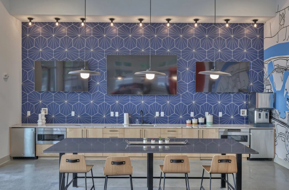 A kitchen with a blue patterned wall and a table with four chairs.