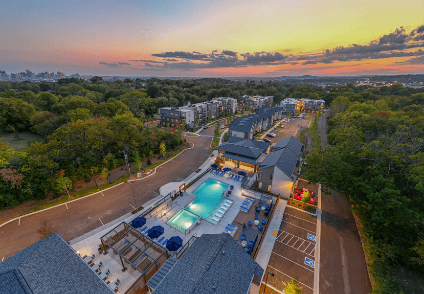 A sunset view of a resort with a pool and a parking lot.