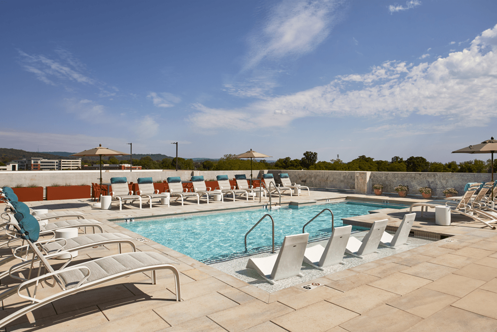A pool with sun loungers and a blue sky.