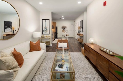 A living room with a white couch, a coffee table, and a guitar picture frame on the wall.