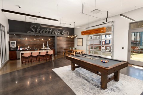A room with a pool table and a bar area.