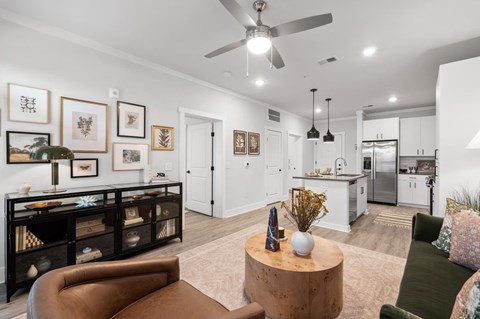 A living room with a brown leather couch, a wooden coffee table, and a ceiling fan.