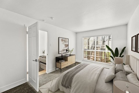 A bedroom with a large bed and a window with blinds.