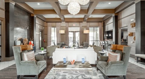 A spacious living room with a grey sofa set and a patterned rug.