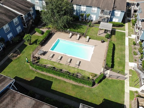 A swimming pool surrounded by a grassy area and a few trees.