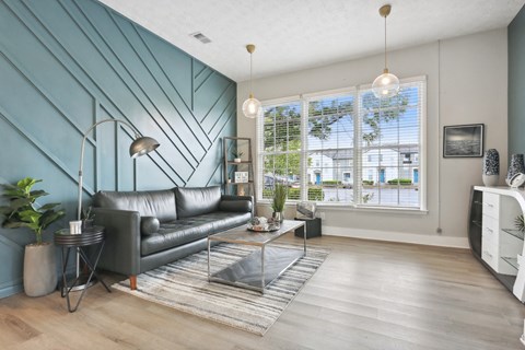 A living room with a black leather sofa and a grey rug.