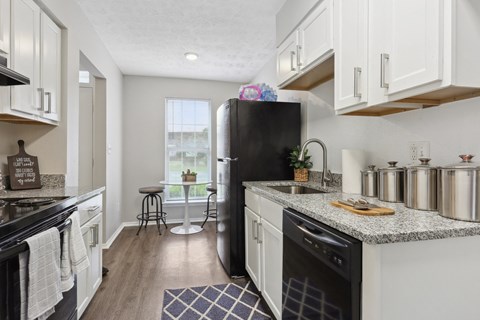 A kitchen with white cabinets and a black refrigerator.