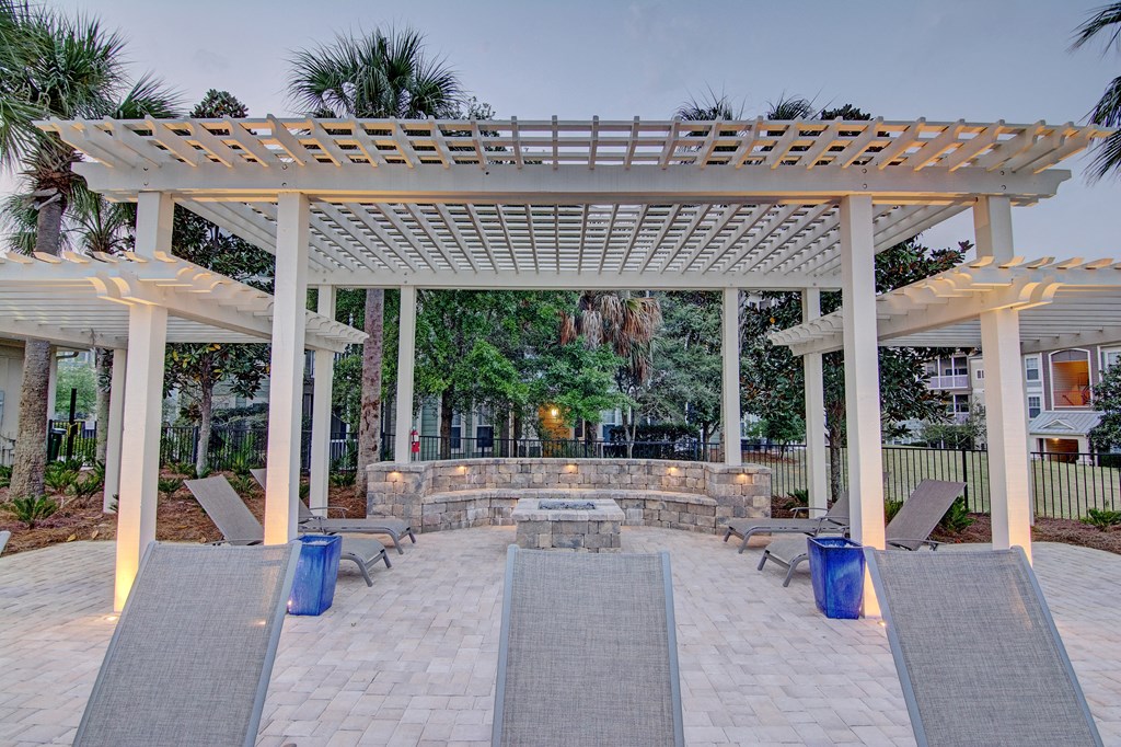 A patio with a white pergola and grey tiles.