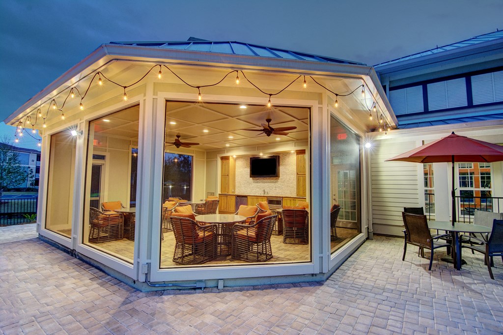 A patio with a table and chairs is lit up at night.
