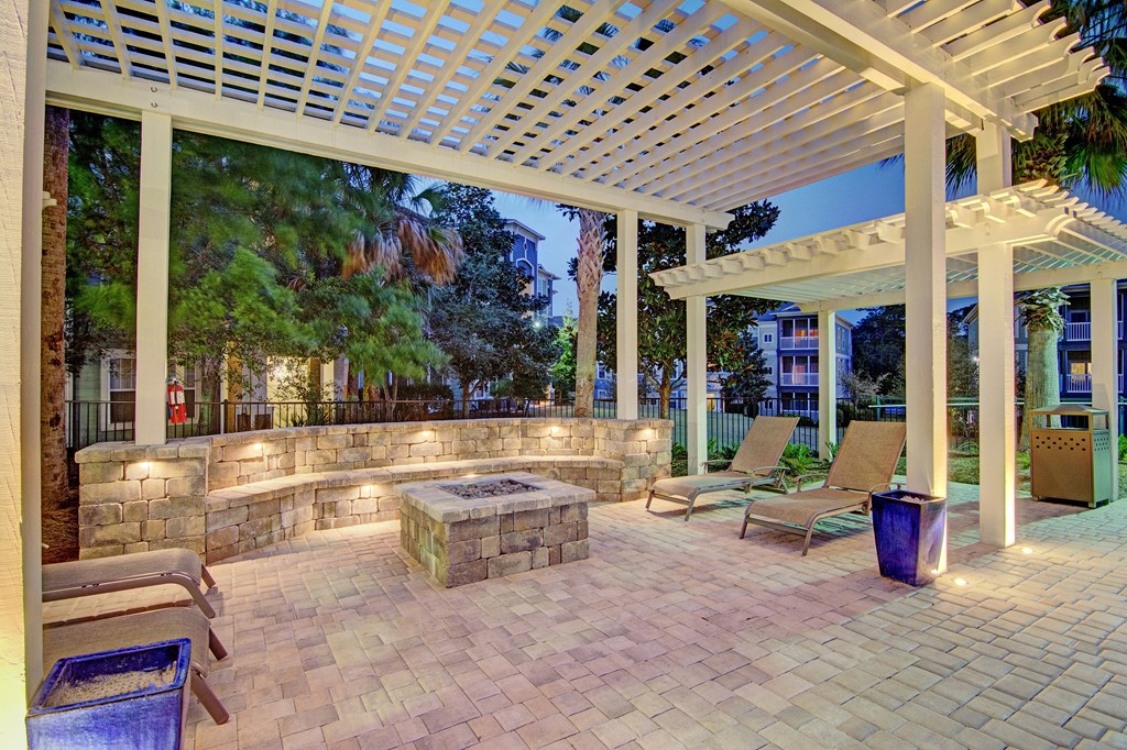 A patio with a white pergola and a stone wall.