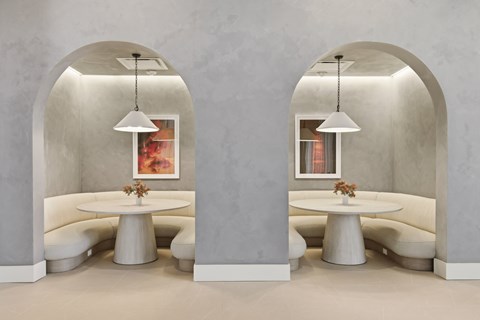 A modern dining area with two round tables and chairs under arched ceilings.