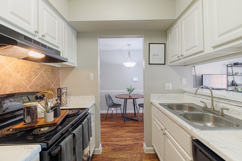 A kitchen with a black stove top oven and white cabinets.