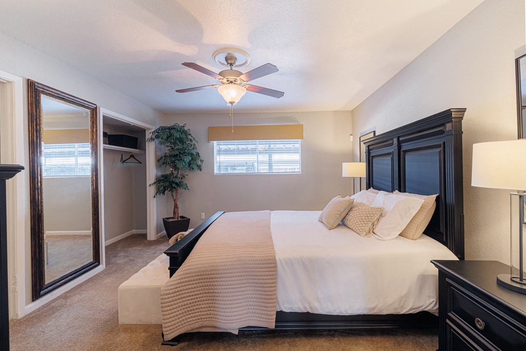 A bedroom with a large bed and a ceiling fan.