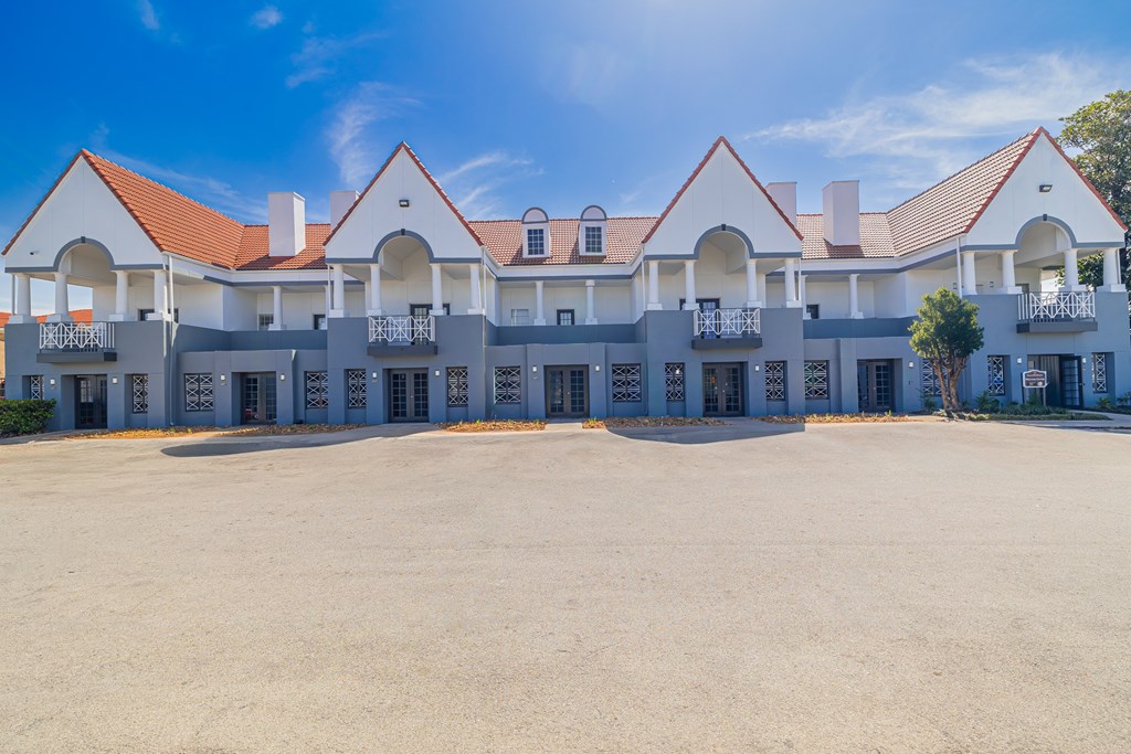 A large white building with red roofs and balconies.
