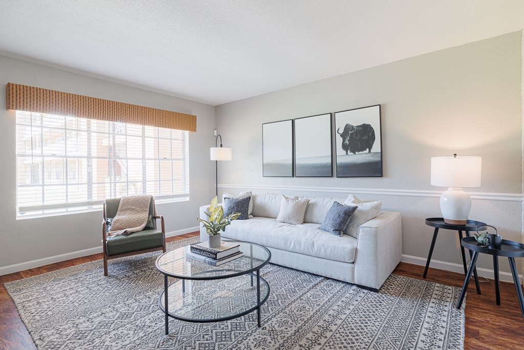 A living room with a white couch, a coffee table, and a window with blinds.