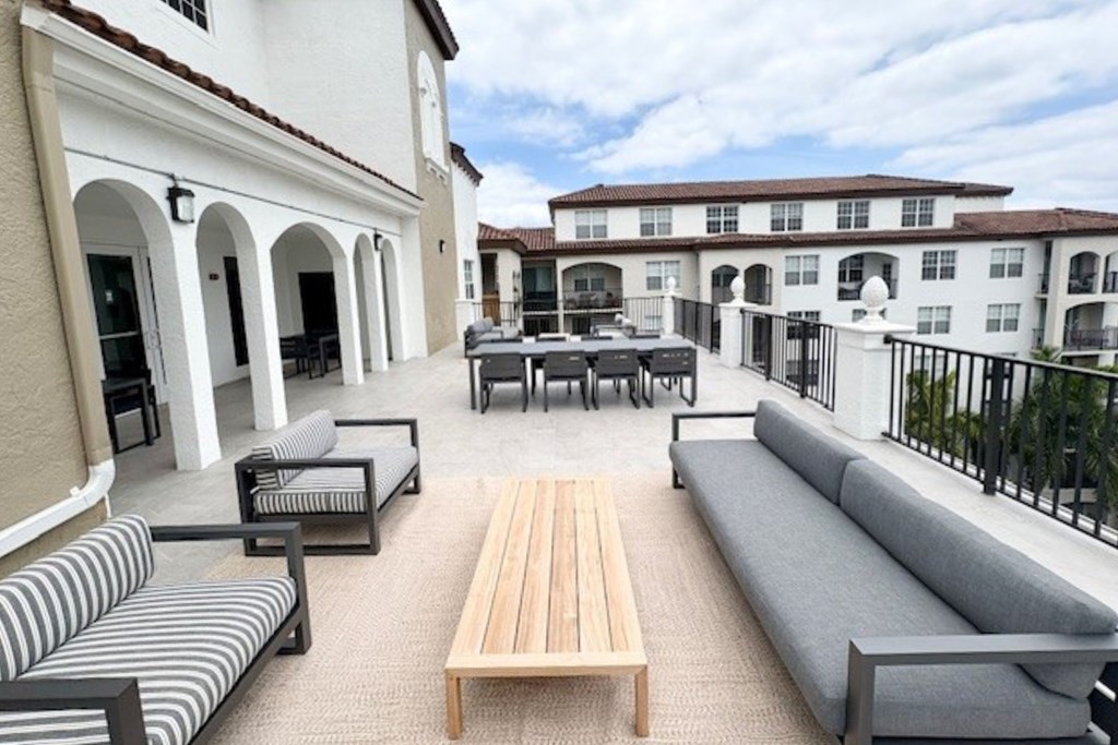 A patio with a table and chairs is surrounded by a white building.