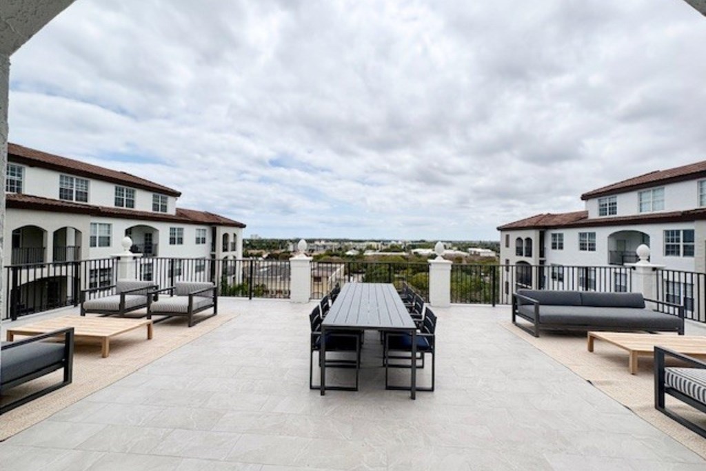 A patio with a table and chairs is surrounded by white buildings.