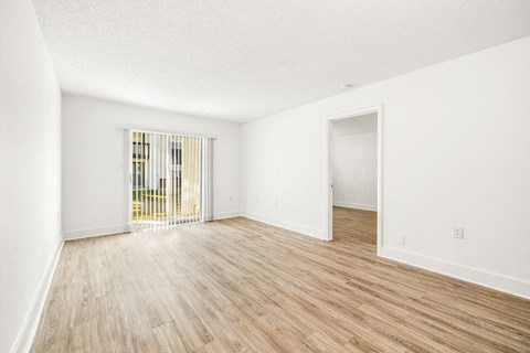 an empty living room with wood flooring and a window
