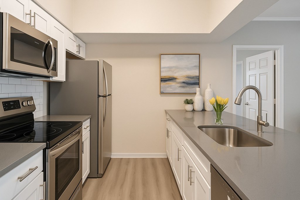 A kitchen with a stove, microwave, refrigerator, and sink.