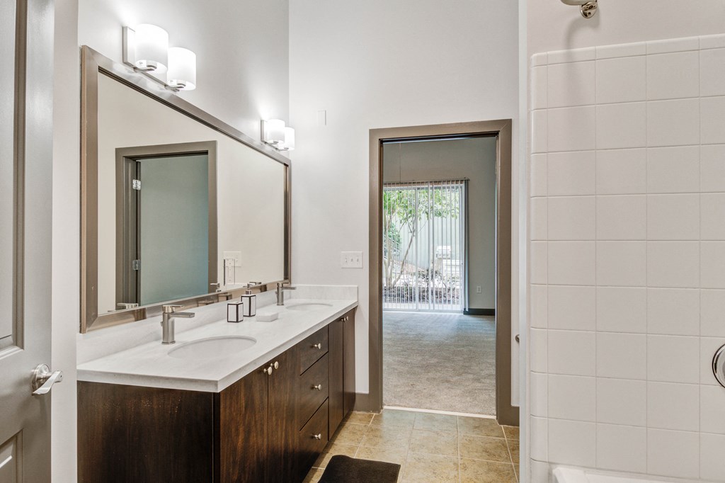 a bathroom with a sink and a mirror and a door to a shower