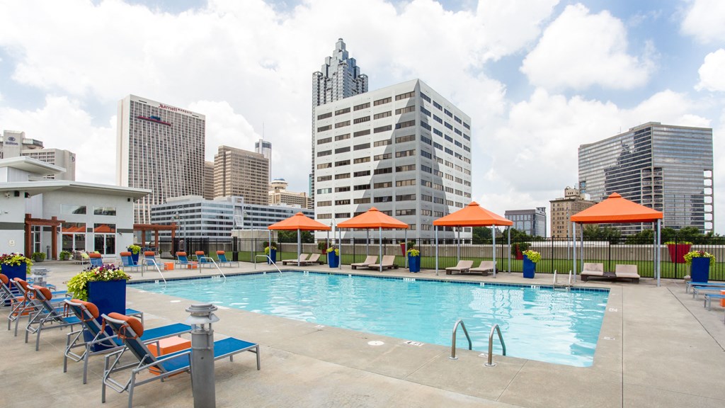a swimming pool with chairs and umbrellas next to a city skyline