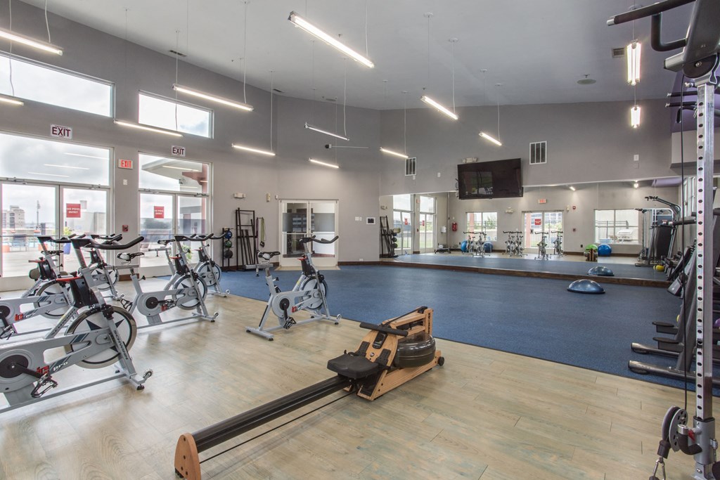 a gym with cardio equipment and weights on a wooden floor