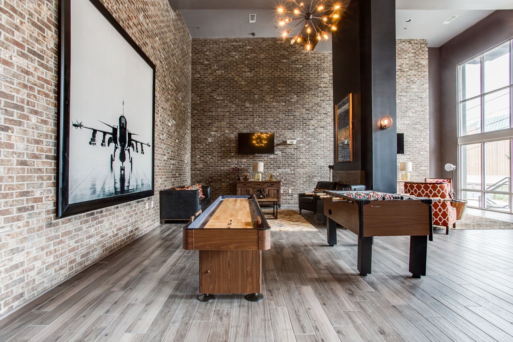 a game room with two pool tables and a painting on a brick wall