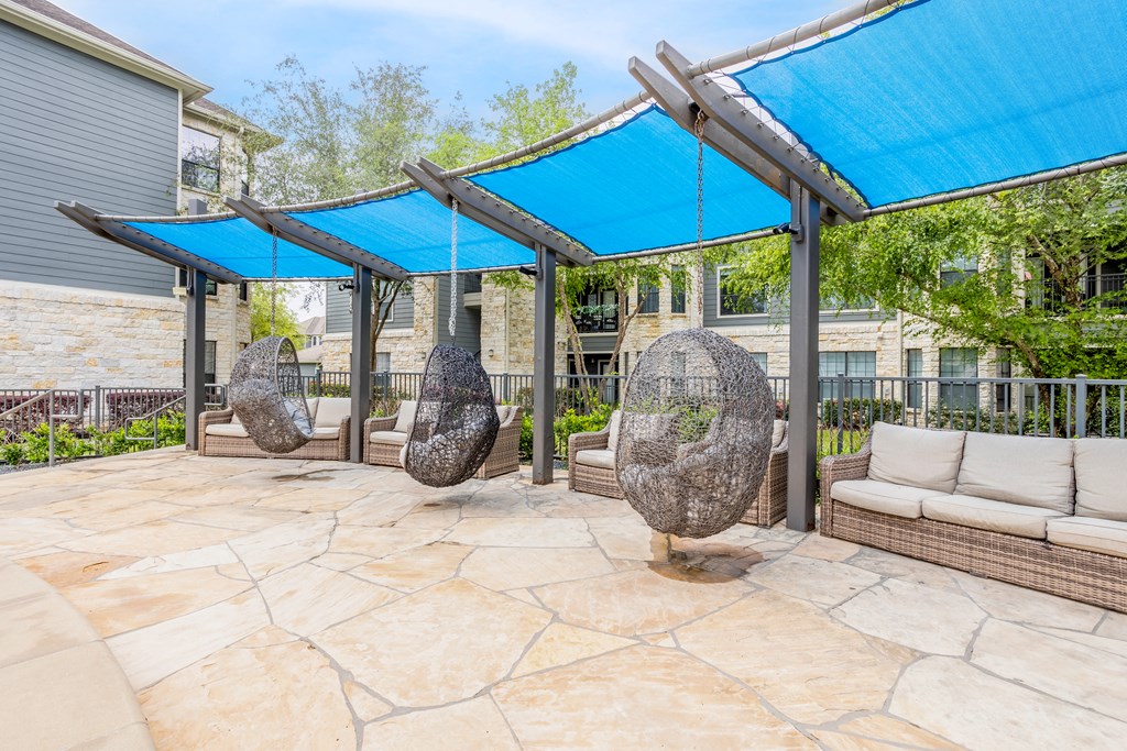 the backyard has a patio with swings and umbrellas