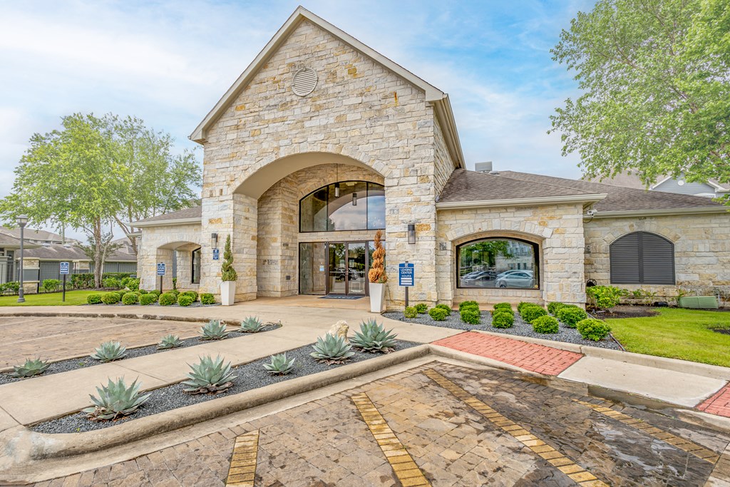 the front entrance of a stone building with a courtyard and landscaping