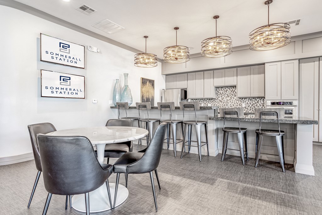 a communal area with a kitchen and bar with chairs and tables