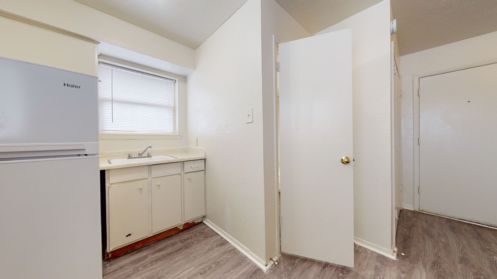 A kitchen with a fridge, sink and cabinets.