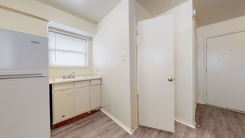 A kitchen with a fridge, sink and cabinets.