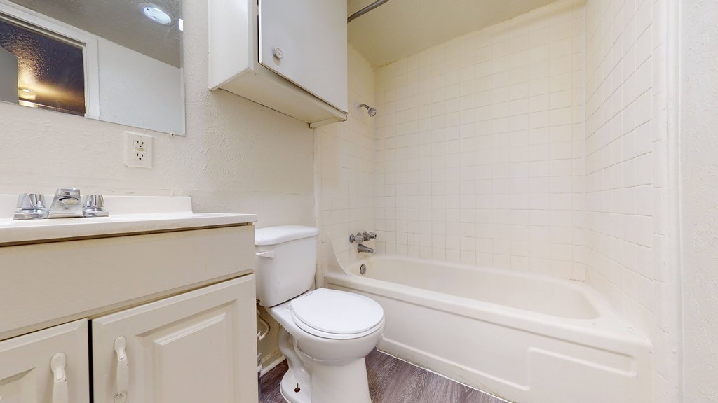 A white toilet sits in a bathroom next to a bathtub.