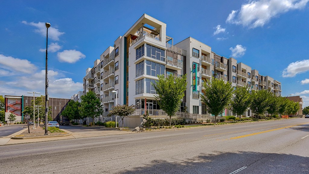 a large apartment building with balconies and a street in front of it