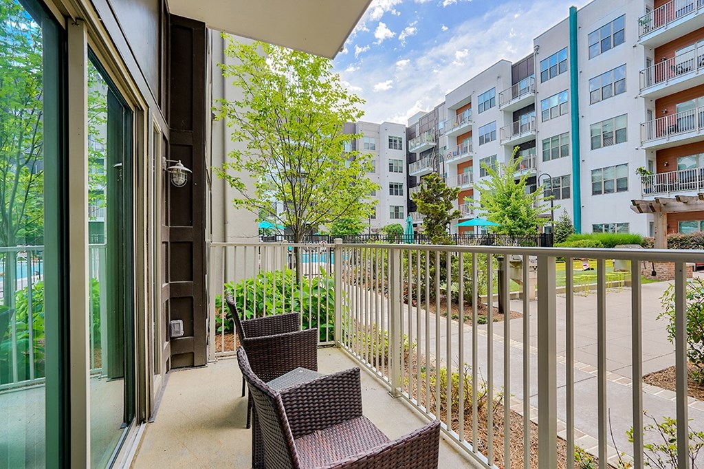 a balcony with two wicker chairs and a sliding glass door