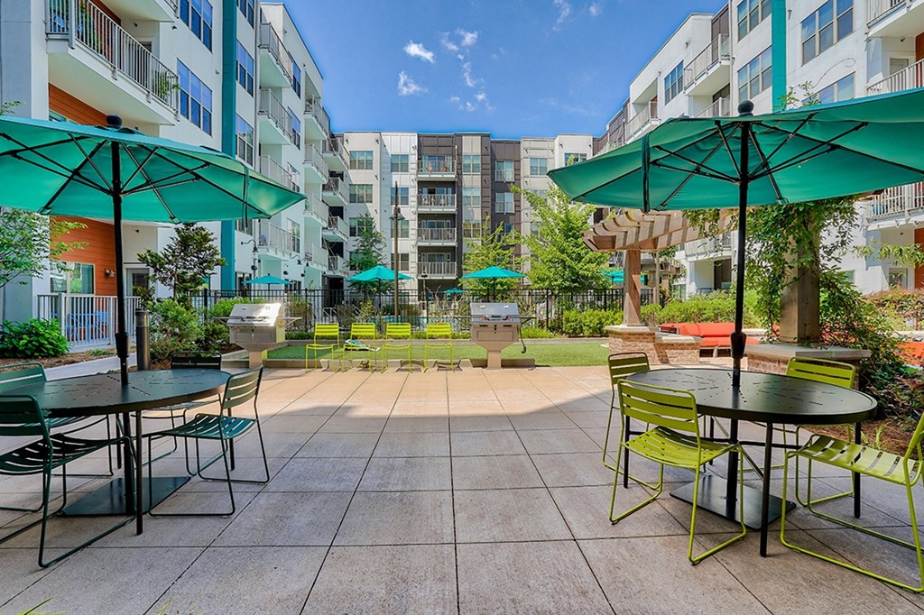 an outdoor patio with tables and green umbrellas