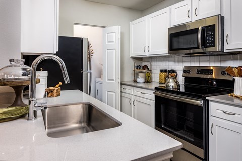 a kitchen with white cabinets and black appliances and a sink