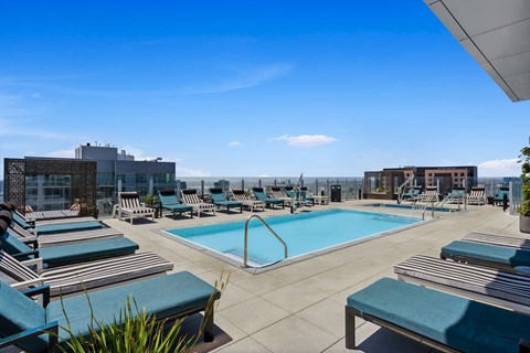 A large swimming pool with lounge chairs and a building in the background.
