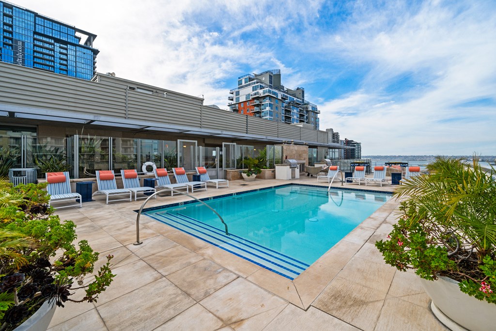 a swimming pool with chairs and a building in the background