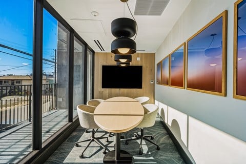 A conference room with a table, chairs, and a television.
