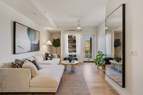A living room with a beige couch and a large painting on the wall.
