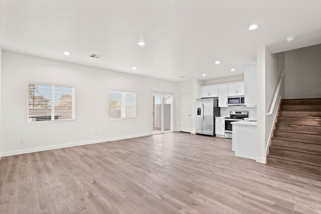 a living room with a staircase and a kitchen