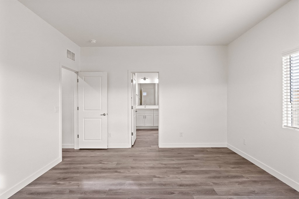 an empty bedroom with white walls and wood flooring