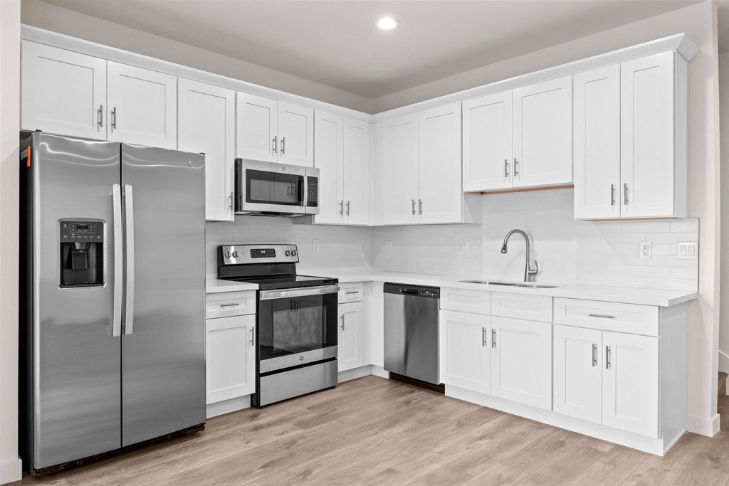 a white kitchen with stainless steel appliances and white cabinets